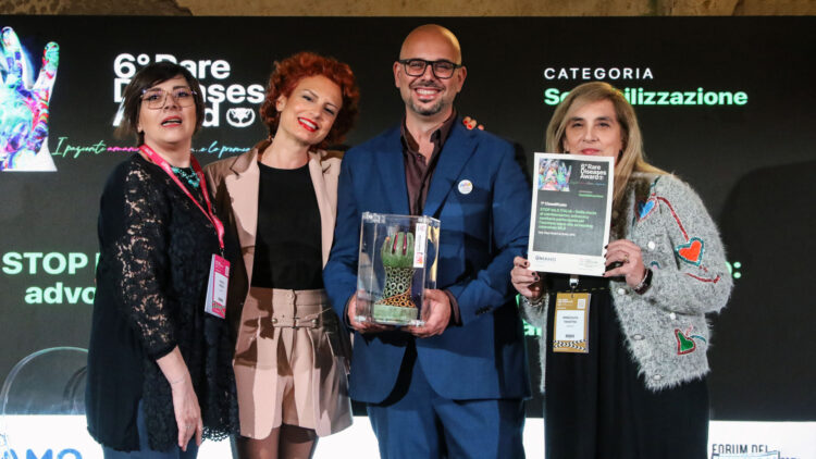 Guido De Barros e Caterina Ceccuti con altre due partecipanti sul palco del Rare Diseases Award 2026, con trofeo e attestato del primo premio.