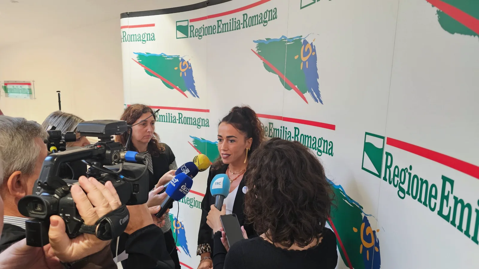 Giulia Ferrari risponde alle domande dei giornalisti, davanti ai microfoni e alle telecamere, nella sede della Regione Emilia-Romagna.