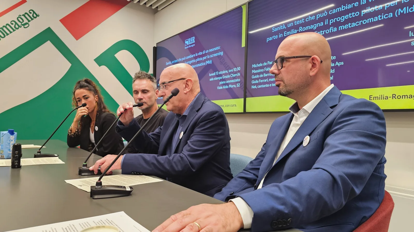Massimo Fabi interviene al microfono; al tavolo siedono anche Giulia Ferrari, Nek e Guido De Barros, in primo piano.