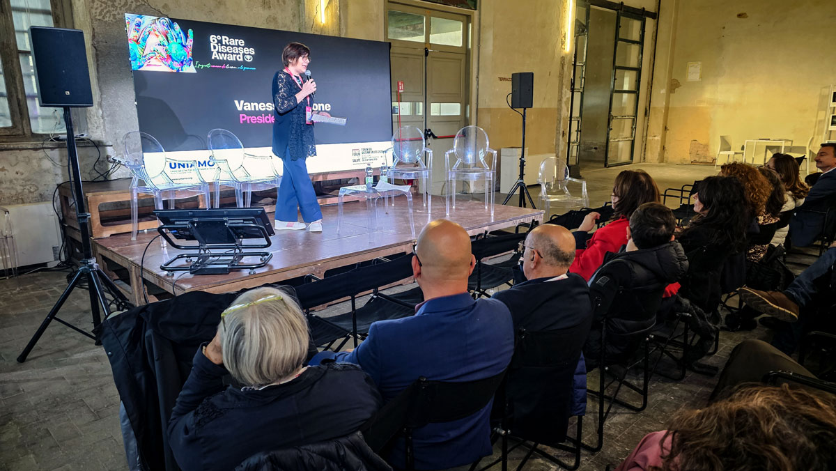 Un intervento al microfono sul palco del Rare Diseases Award, con il pubblico seduto in sala.